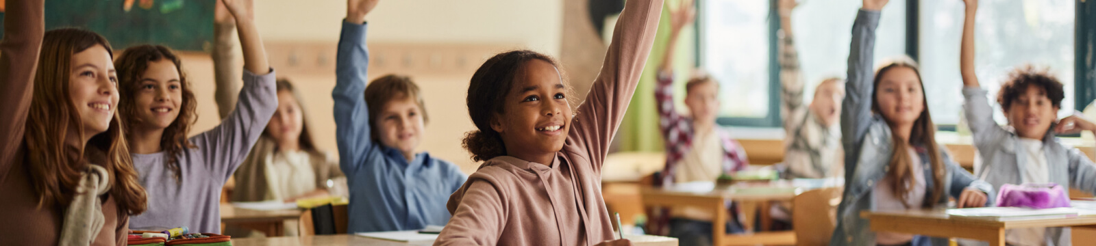 group of students raising their hands in a classroom